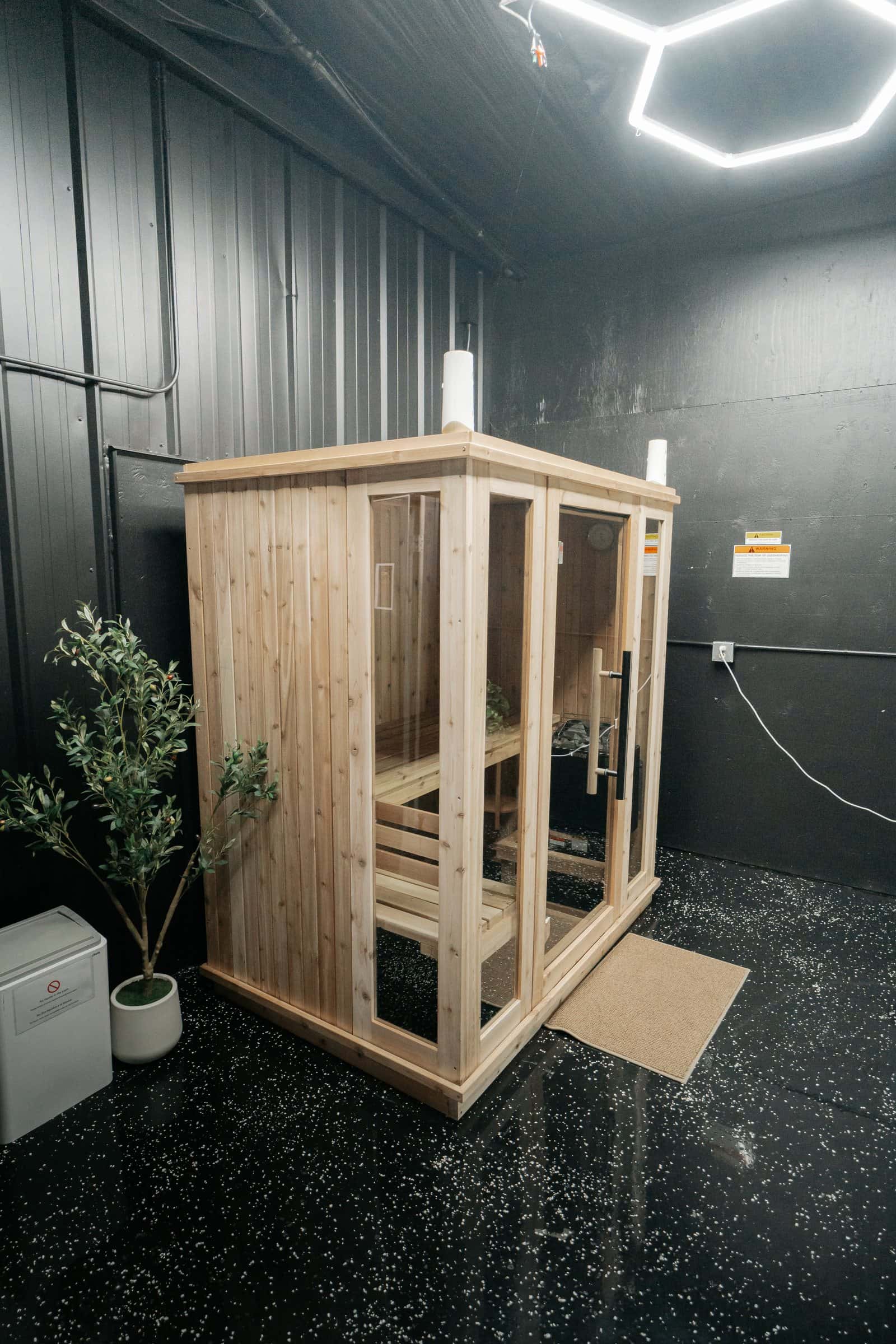 La cabina de sauna de madera bajo luces hexagonales en el techo